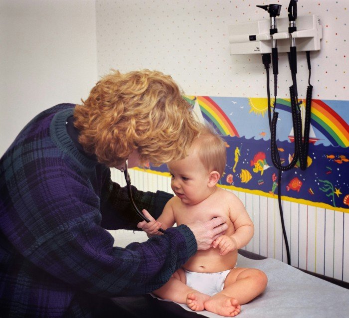 Healthcare professional examining a baby with a stethoscope during a pediatric checkup.